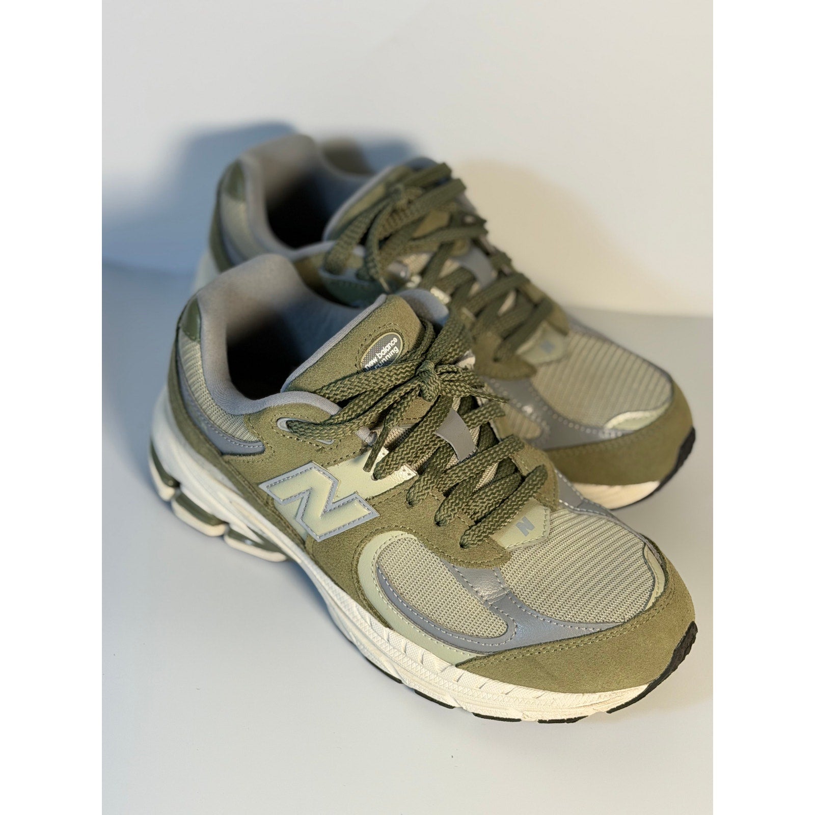 Pre-owned New Balance 2002R athletic running sneakers in olive and gray for youth size 5.5, featuring a sporty design and comfortable fit.
