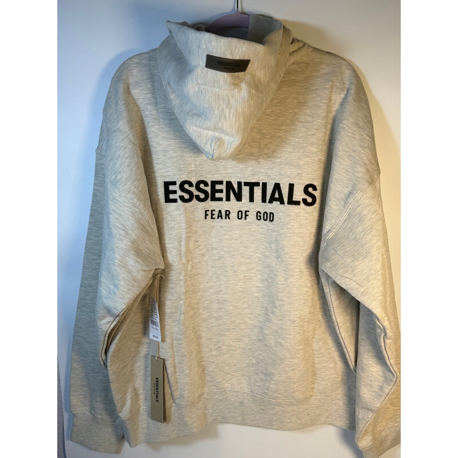 Fear of God ESSENTIALS men's light oatmeal pullover hoodie with logo, casual sweatshirt featuring a relaxed fit and soft fabric.