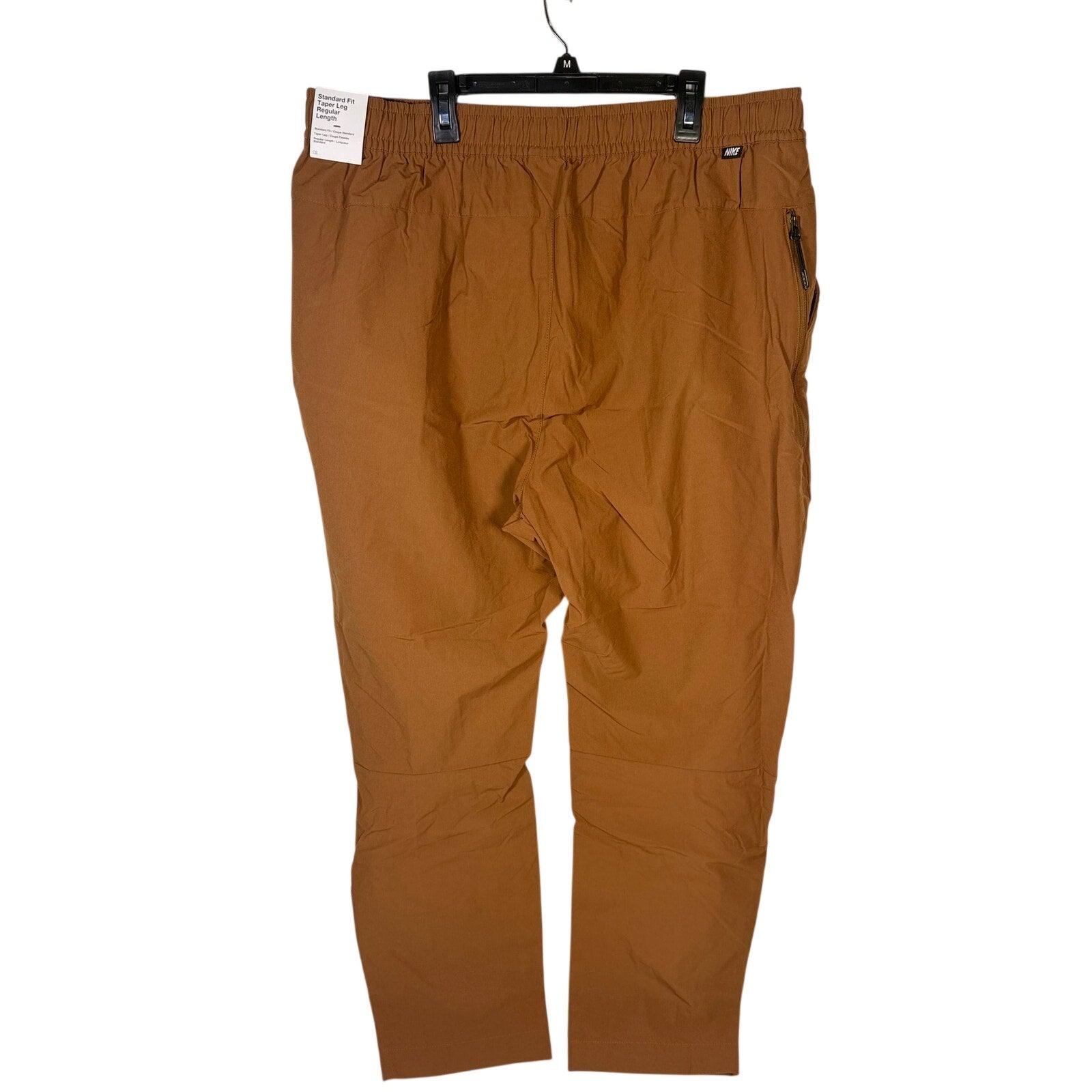Nike Sportswear men's woven brown cacao pants with elastic waist, size XXL, showing the relaxed fit and fabric texture.