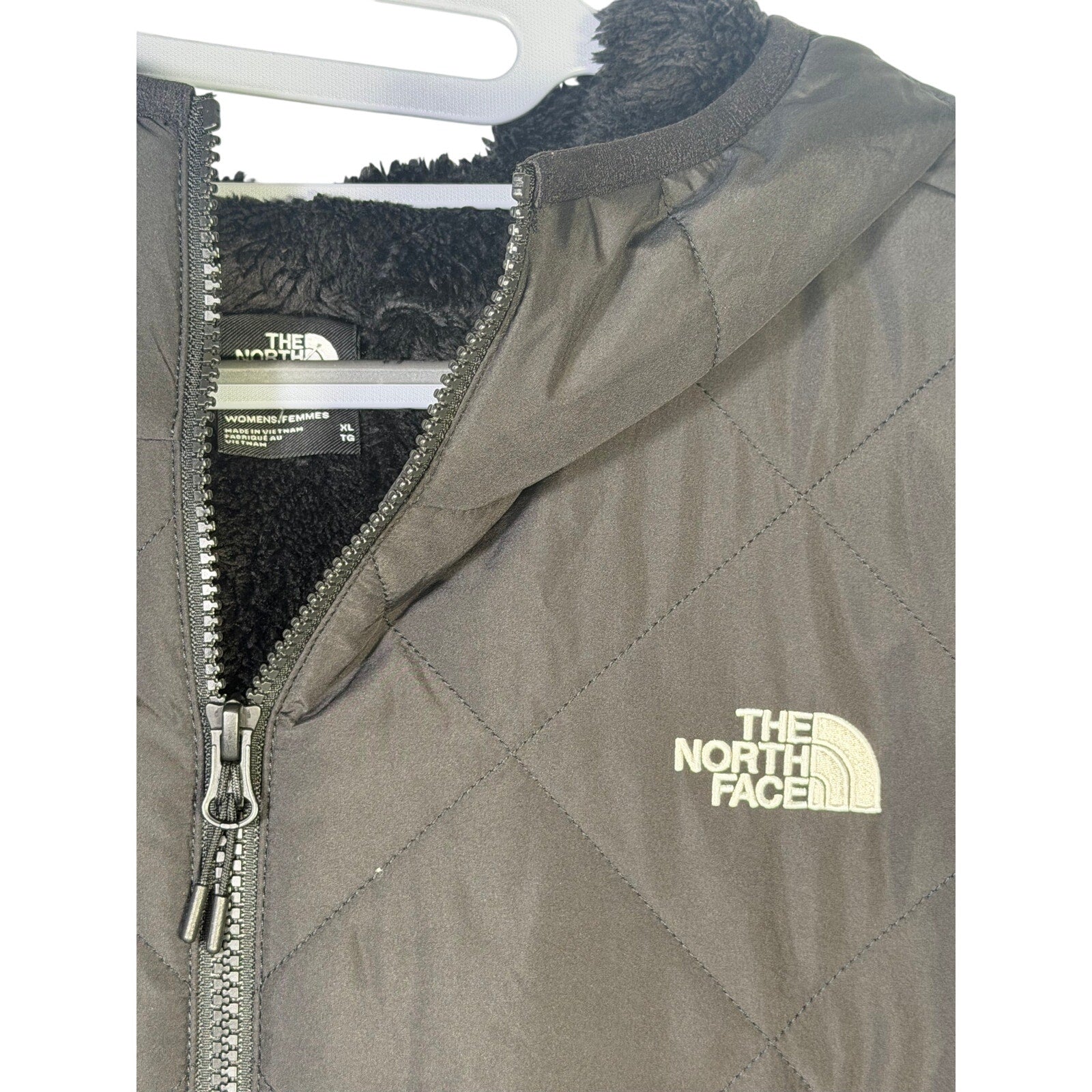 The North Face Women's Shady Glade insulated parka in black, size XL, displayed on a hanger, showcasing its quilted design and hood.