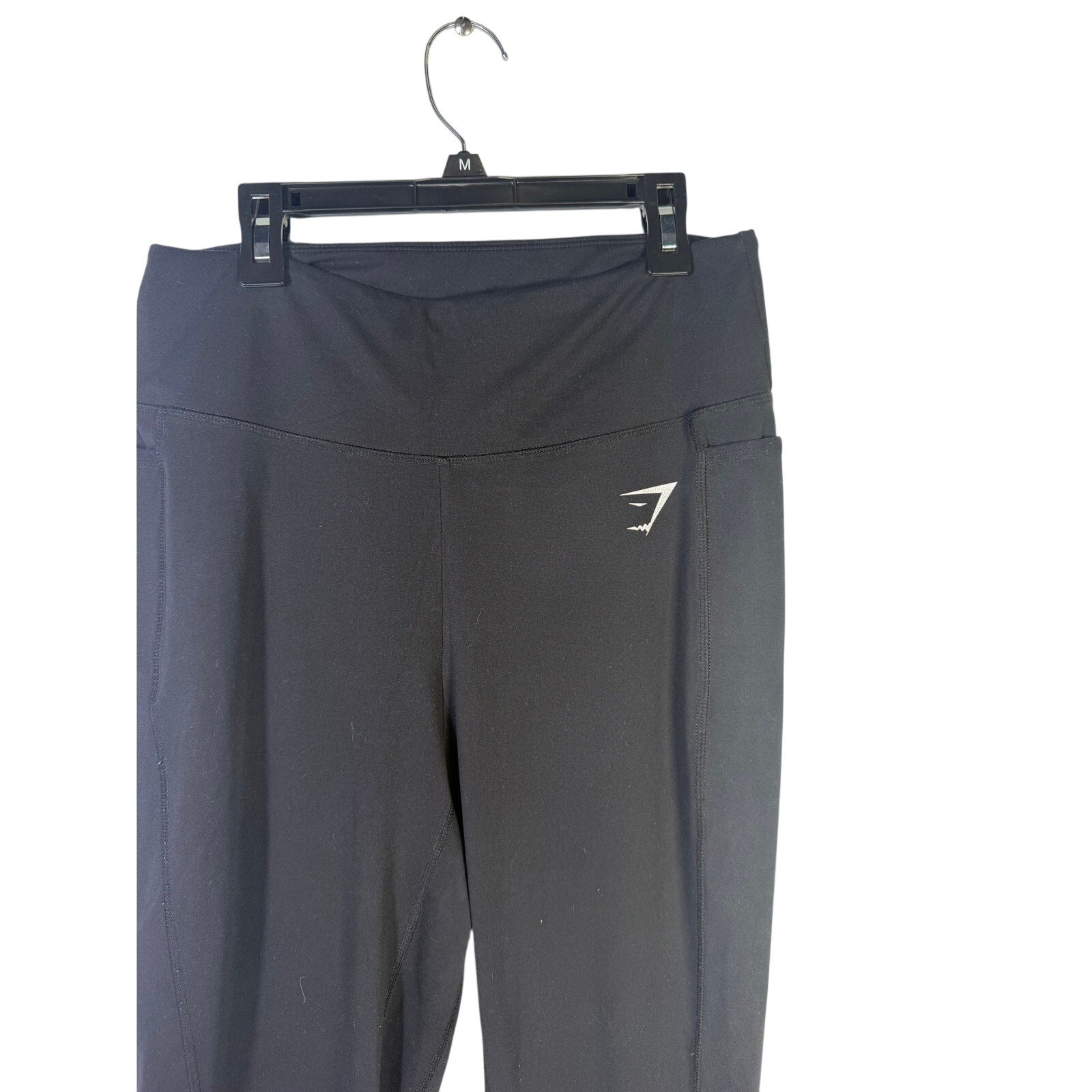 Black Gymshark women’s high-waisted leggings with side pockets, shown flat on a white background, size L.