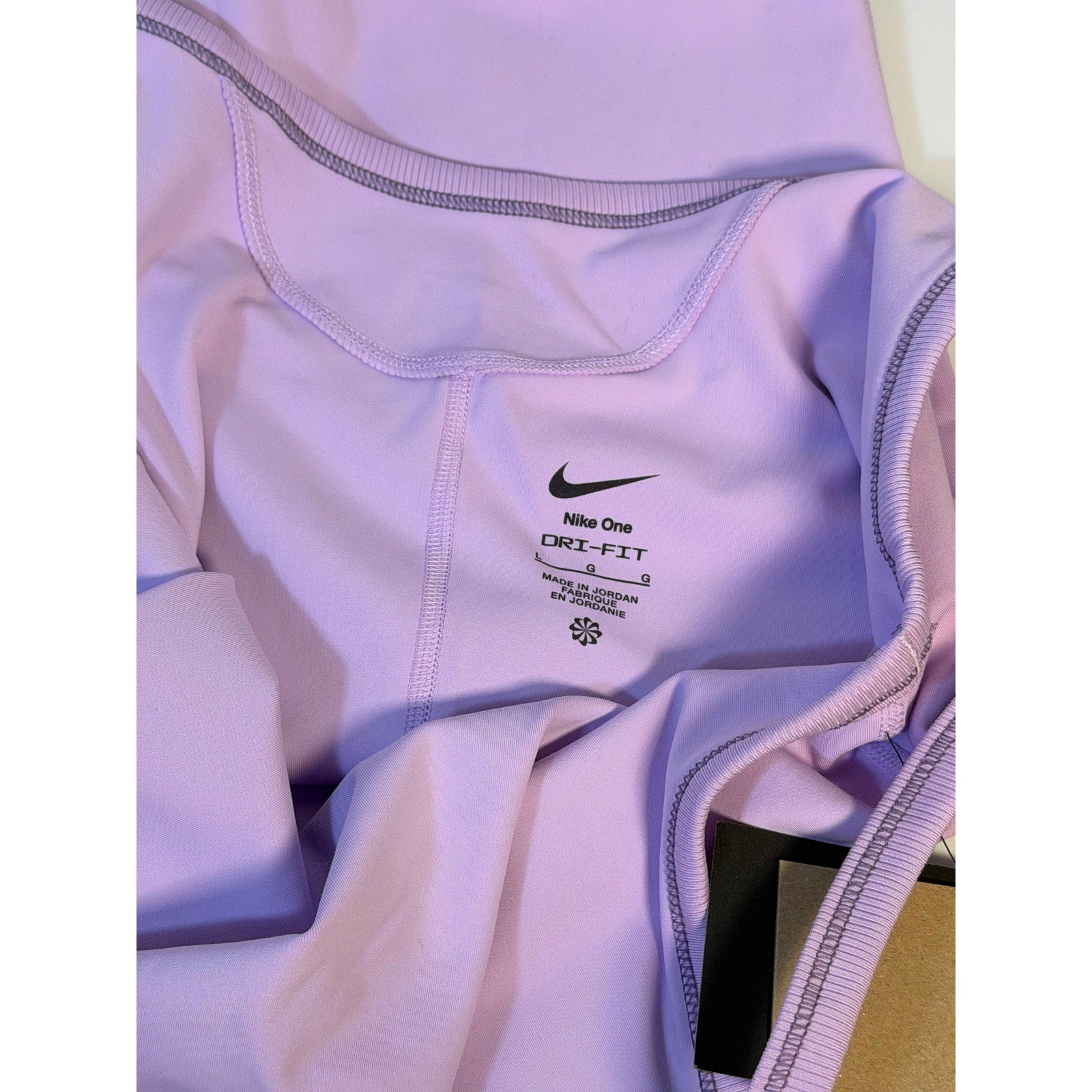Nike women's lavender Dri-FIT training romper bodysuit, large size, shown on a hanger with a close-up of fabric details.