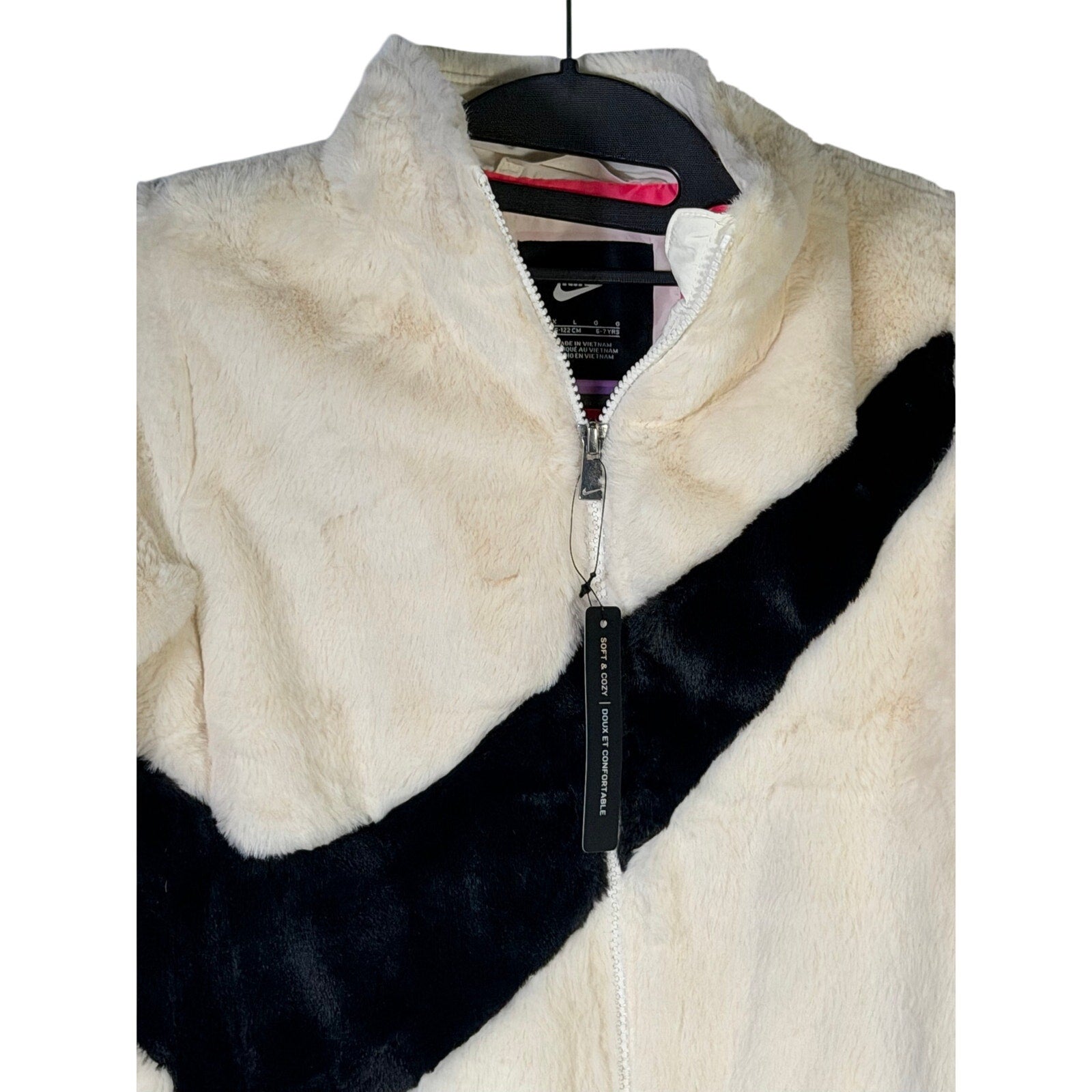 Nike girls’ faux fur full zip jacket in cream and black, size 6X, featuring an oversized swoosh logo and plush texture.
