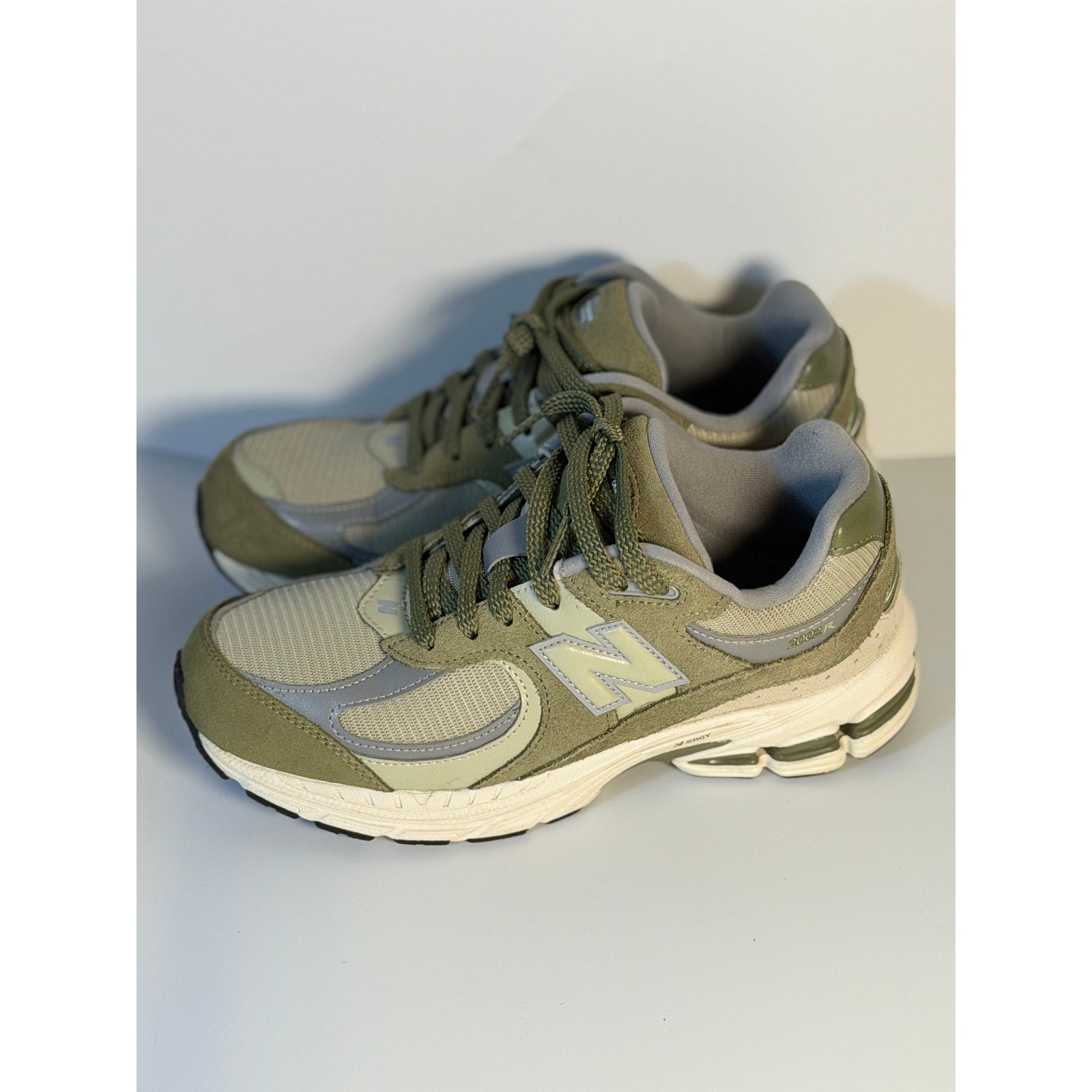 Pre-owned New Balance 2002R athletic running sneakers in olive and gray for youth size 5.5, showing side view and stylish design.