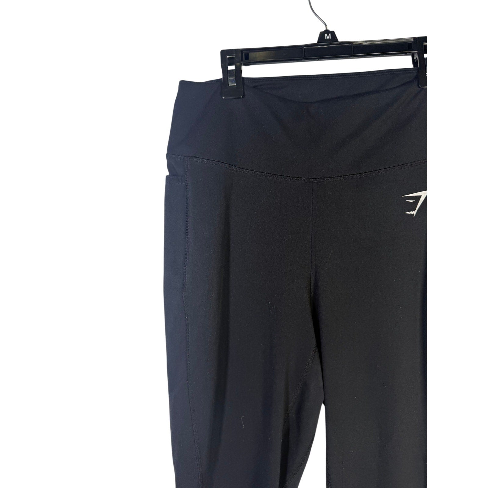 Black Gymshark women’s high-waisted leggings with side pockets, shown on a model, size large, made for active wear and comfort.