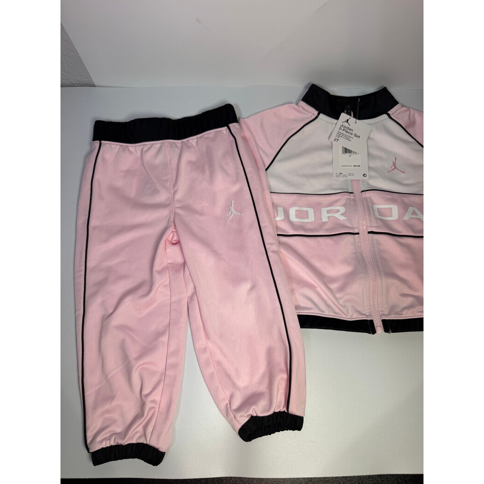 Jordan toddler girls pink and black 2-piece track jacket and pants set, size 2T, with sporty design and brand logo.