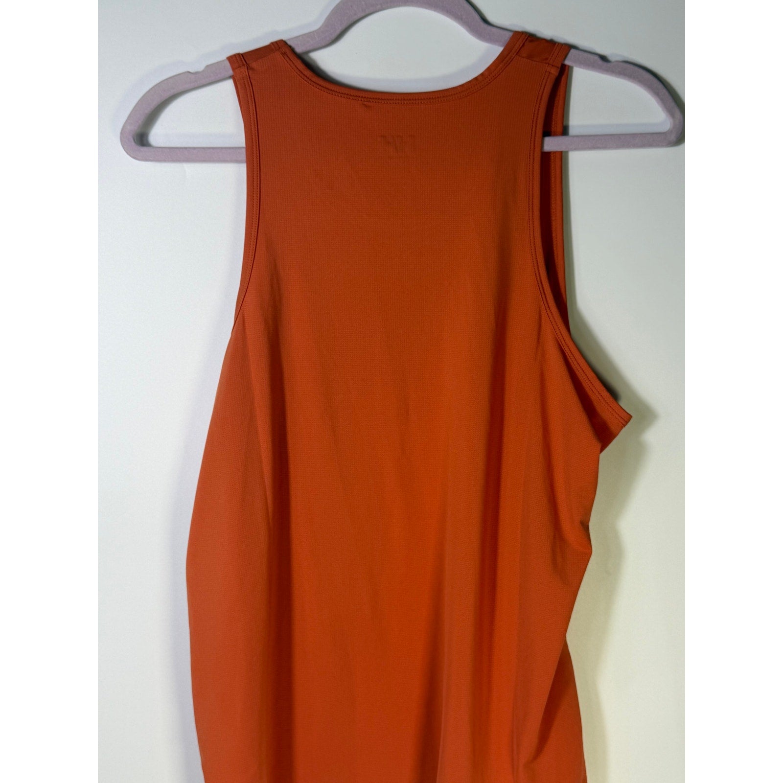Helly Hansen women's orange active tank top with sleeveless design and drawstring hem, suitable as a sports bra or workout top.