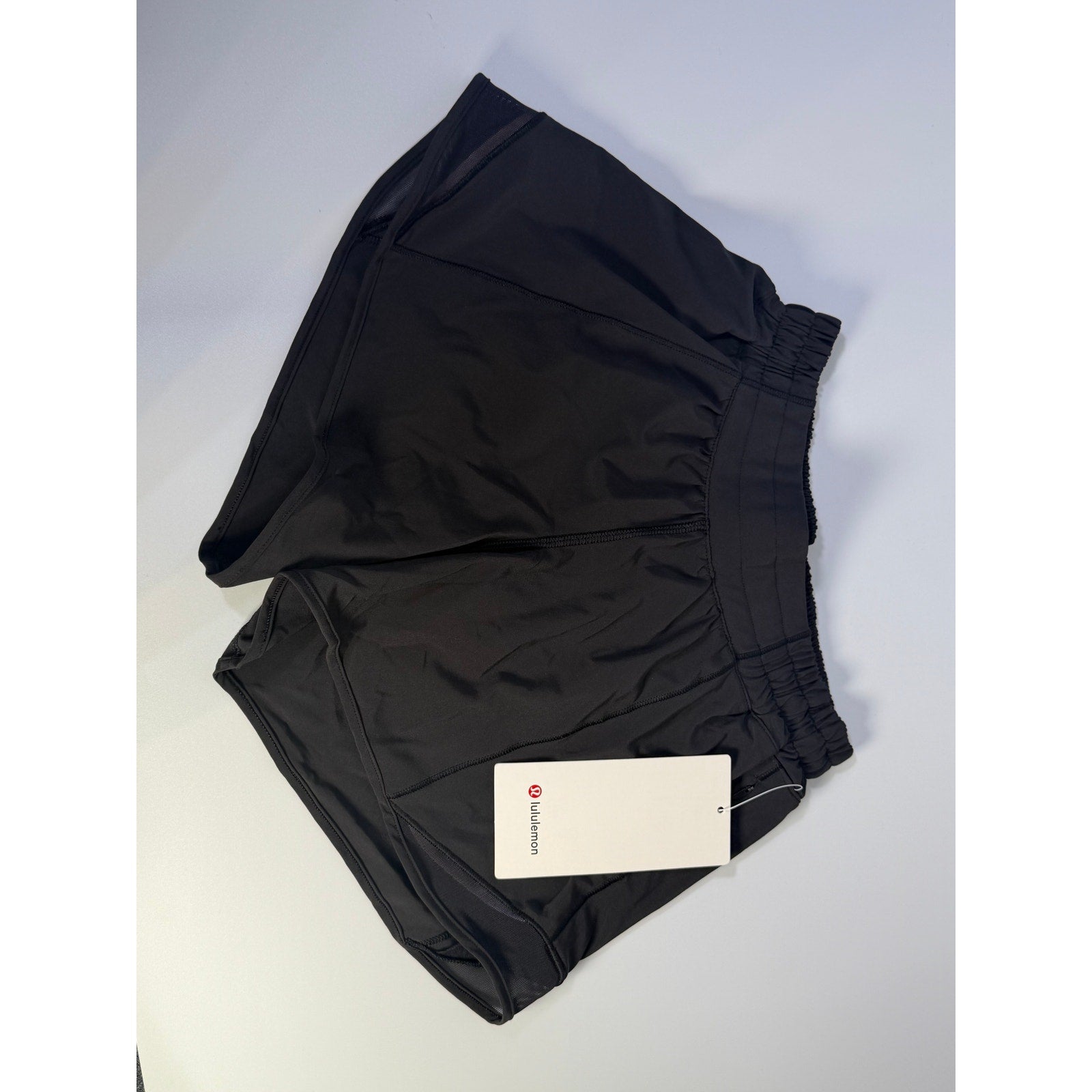 Black Lululemon Hotty Hot Low Rise Lined Shorts for women, size 4, displayed on a hanger with a close-up of the fabric.