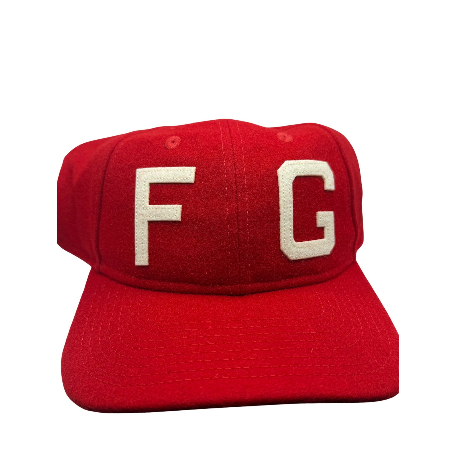 Fear of God x New Era 59FIFTY fitted hat in red and cream with FG logo, showing front view and structured design.