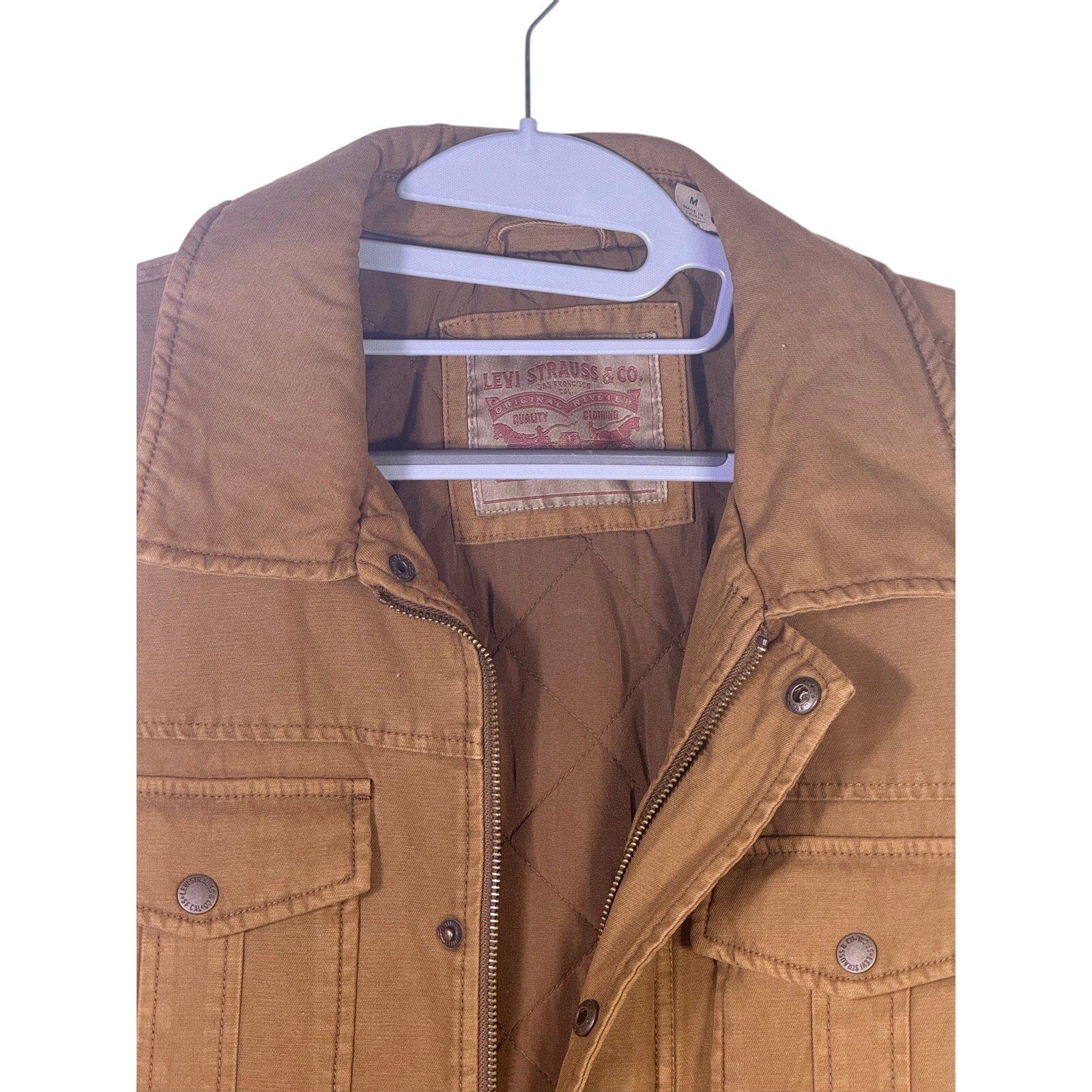 Levi’s men’s tan canvas quilted utility field jacket, size medium, displayed on a hanger, showing front view with quilted details.