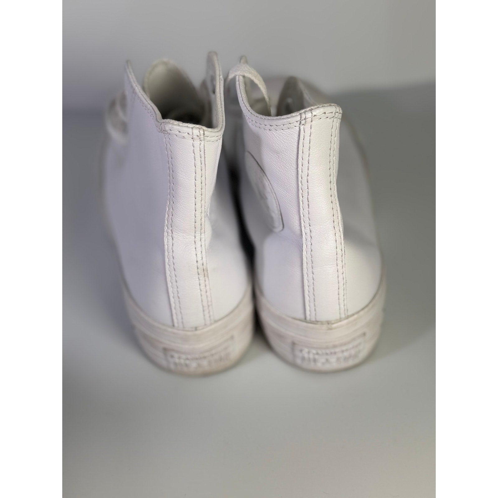 White leather Converse Chuck Taylor All Star Lift Hi sneakers with platform sole, women's US 8.5, showing side view and laces.
