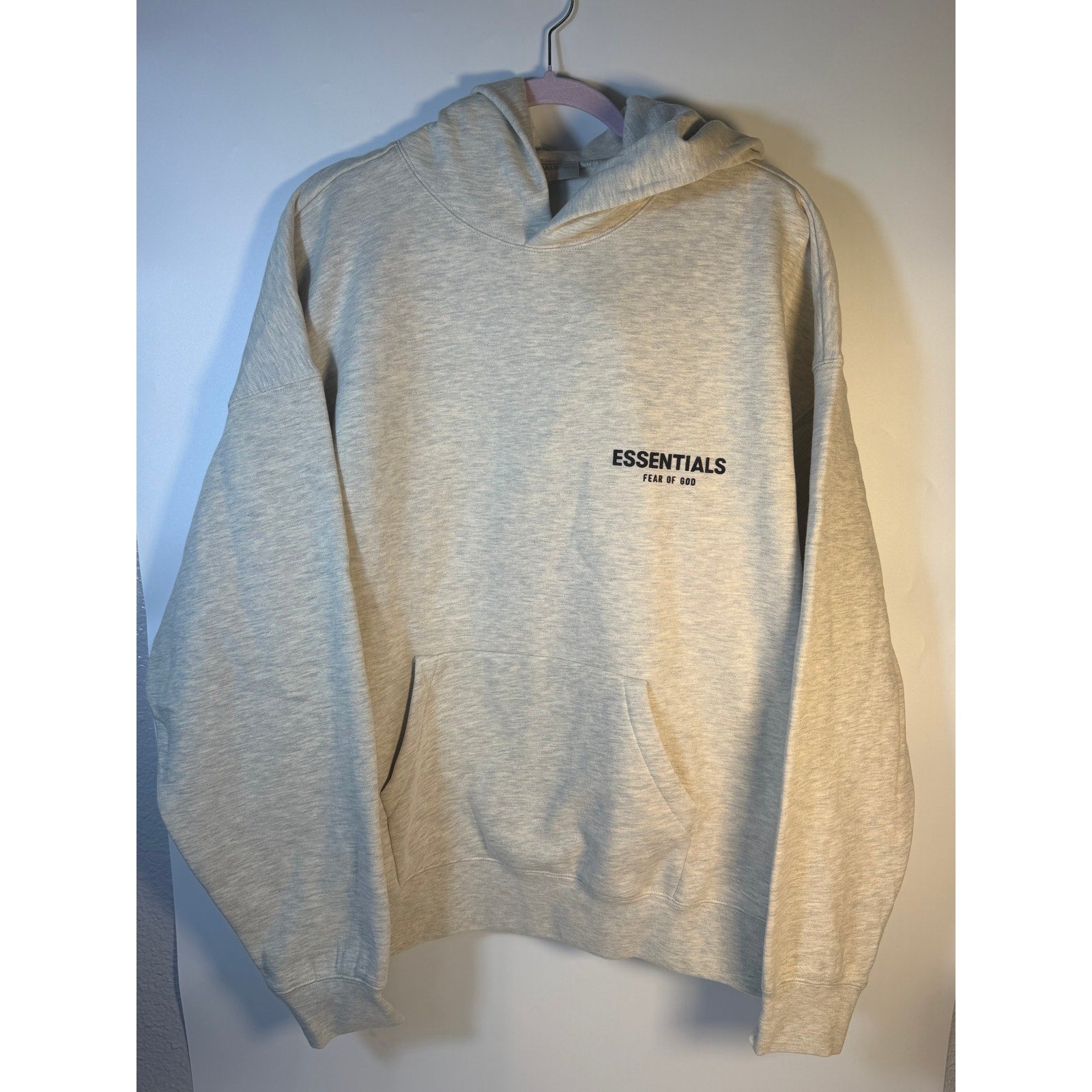 Fear of God ESSENTIALS men's Light Oatmeal pullover hoodie with logo, front view, showcasing casual sweatshirt design.